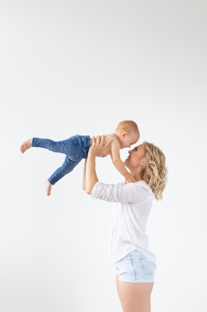 Mãe feliz com bebê adorável na parede branca