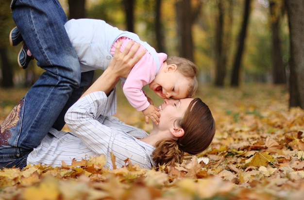 Mãe feliz com bebê se divertindo no parque de outono