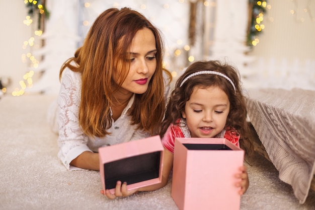 Mãe feliz com criança olhando para dentro da caixa de presente de natal