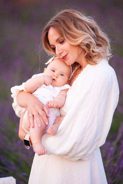 Mãe feliz com filha bonita em fundo lavanda. Mulher bonita e bebê fofo