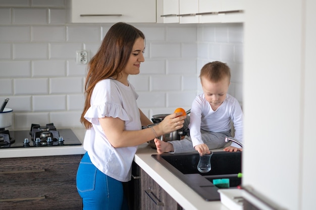 Mãe feliz com menino cozinhando sopa juntos na cozinha em casa