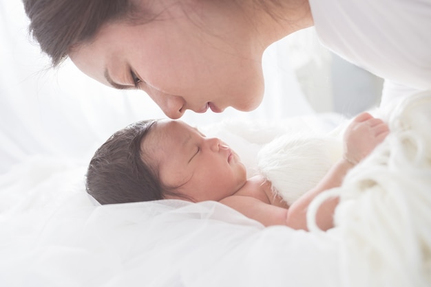 Mãe feliz com o bebê na cama