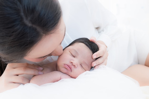 mãe feliz com o bebê na cama