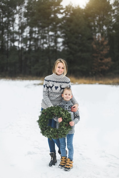 Mãe feliz com o filho pequeno no fundo da floresta de inverno ao ar livre