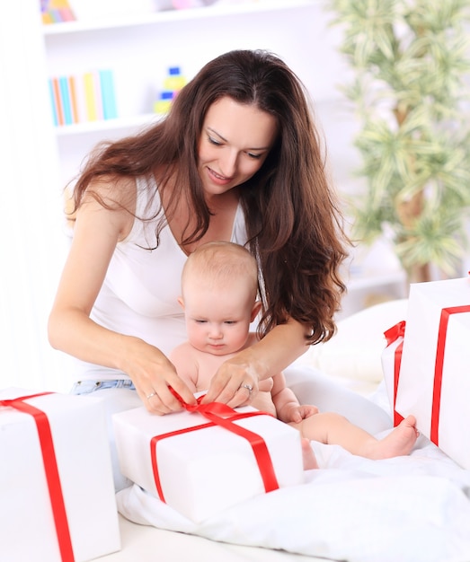 Mãe feliz com seu bebê abrindo uma caixa de presente. conceito da celebração.