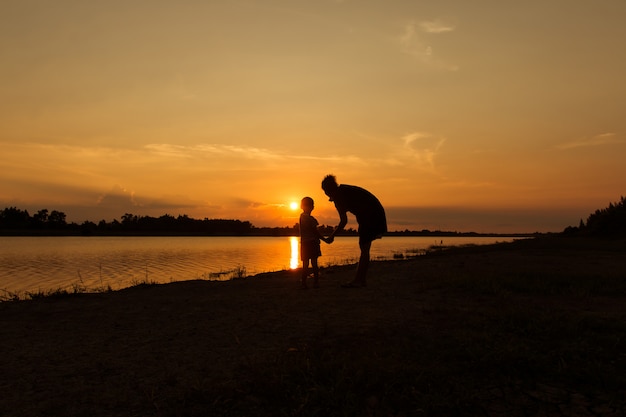 Mãe feliz com seu filho brincar e olhando o pôr do sol