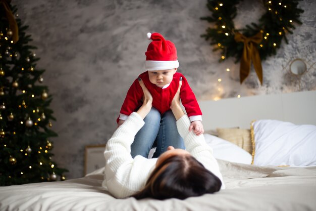 Mãe feliz e adorável bebê no terno do papai noel