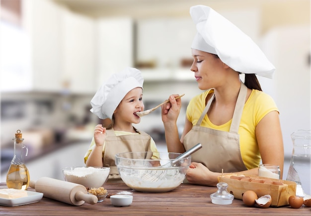 Mãe feliz e filha criança preparando comida