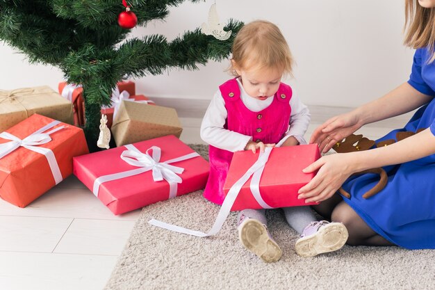 Mãe feliz e jovem abrindo presentes de Natal