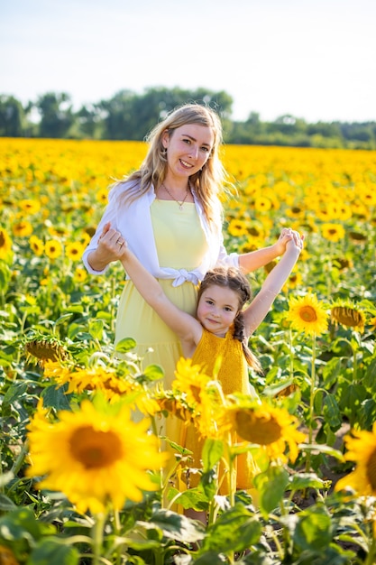 Mãe feliz e sua filha pequena no campo de girassóis