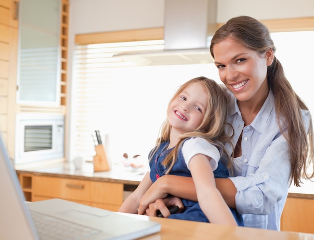 Mãe feliz e sua filha usando um laptop