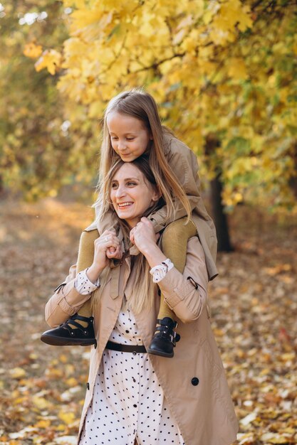 Mãe feliz e sua linda filha se divertem e caminham no parque outono.