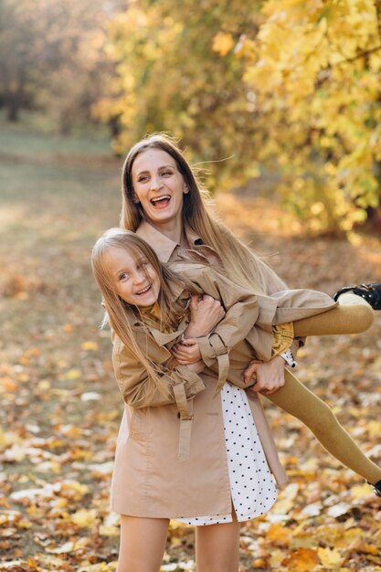 Mãe feliz e sua linda filha se divertem e caminham no parque outono.