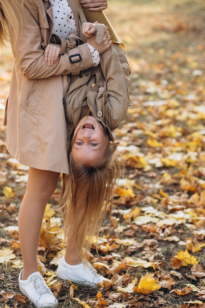 Mãe feliz e sua linda filha se divertem e caminham no parque outono.