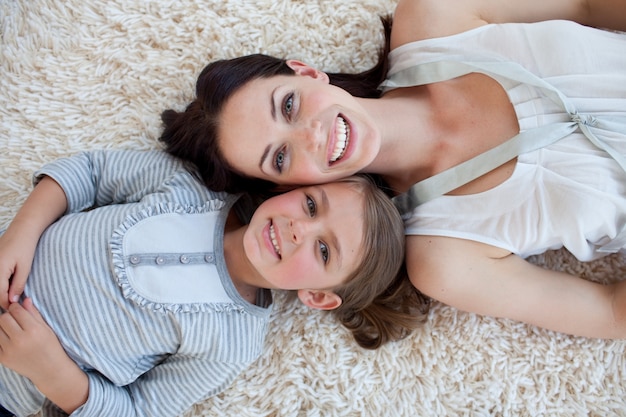 Mãe feliz e sua menina deitada no chão