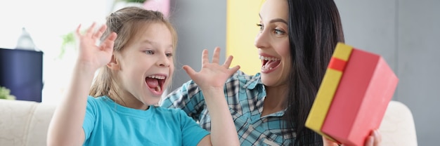 Foto mãe feliz em êxtase com a filha segurando um close da caixa de presente