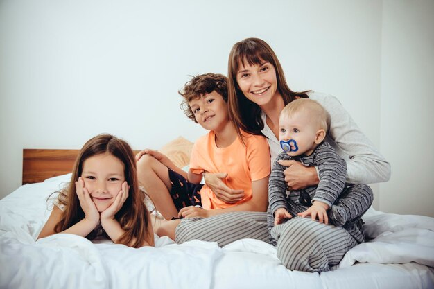 Mãe feliz na cama com seus três filhos