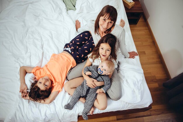 Mãe feliz na cama com seus três filhos