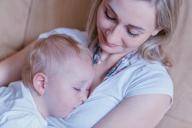 mãe feliz olhando com amor para o bebê adormecido em seus braços