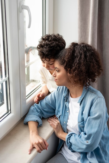 Mãe feliz olhando pela janela com o filho