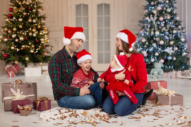 Mãe feliz, pai, filha e filho com chapéu de papai noel