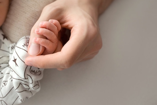 Mãe feliz segurando amorosamente os dedos de um bebê recém-nascido