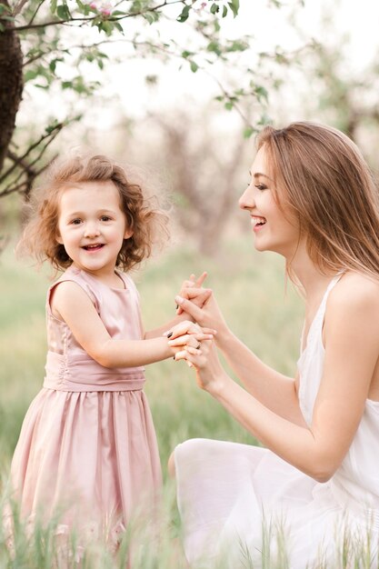 Mãe feliz segurando as mãos de uma menina se divertindo em um prado ao ar livre