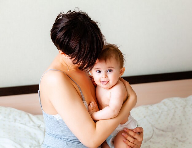 Mãe feliz segurando seu bebê. Mãe beija seu bebê