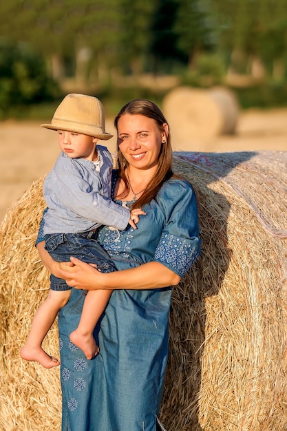 Mãe feliz segurando seu filho nos braços em um campo de grãos Linda mãe e seu filho se divertindo Família feliz