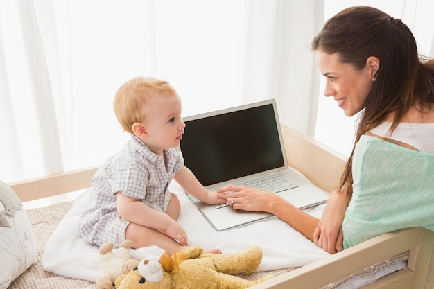 Mãe feliz usando laptop com seu bebê