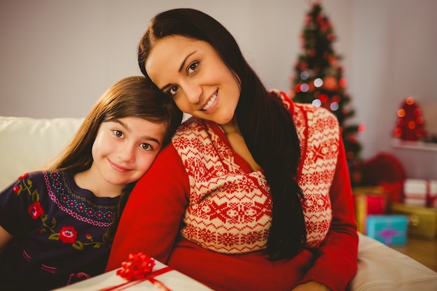 Mãe festiva e filha segurando o presente de natal