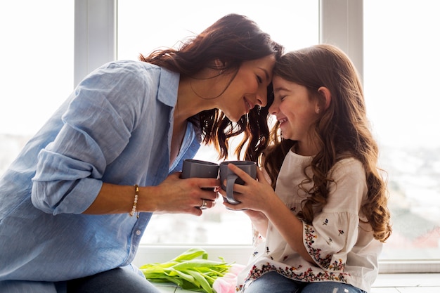 Foto mãe filha, chá bebendo, ligado, peitoril janela