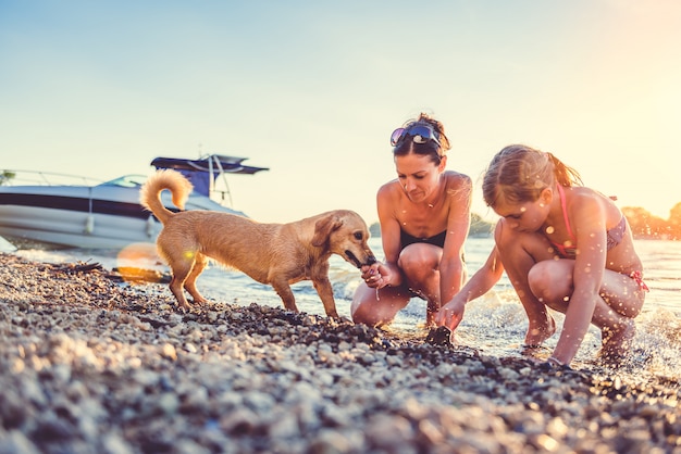 Mãe, filha e cachorro na praia