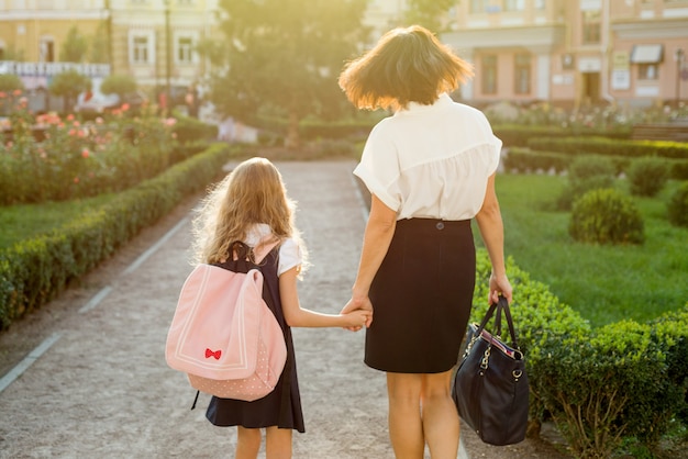 Mãe filha levando a escola, vista traseira.