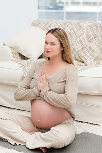 Mãe futura focada fazendo exercícios de ioga no chão