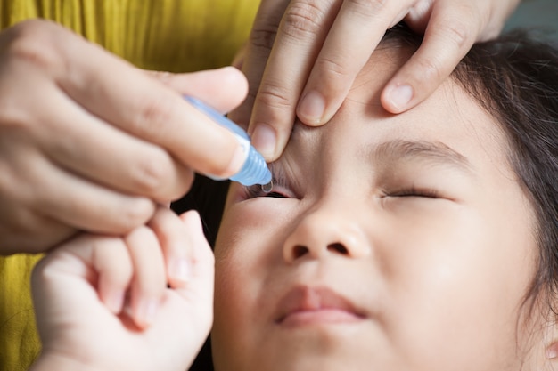 Mãe gotejando remédios para os olhos da criança