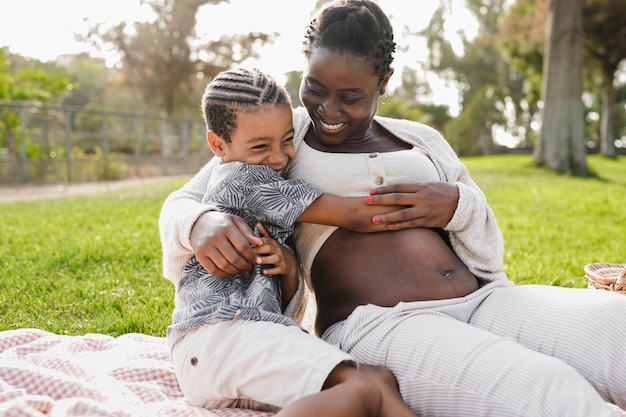 Mãe grávida africana aproveita o dia com filho no parque da cidade Conceito de amor mãe e filho