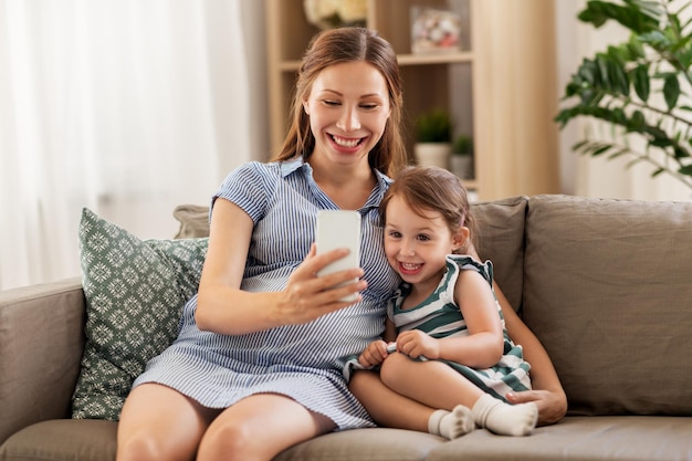 mãe grávida e filha com smartphone