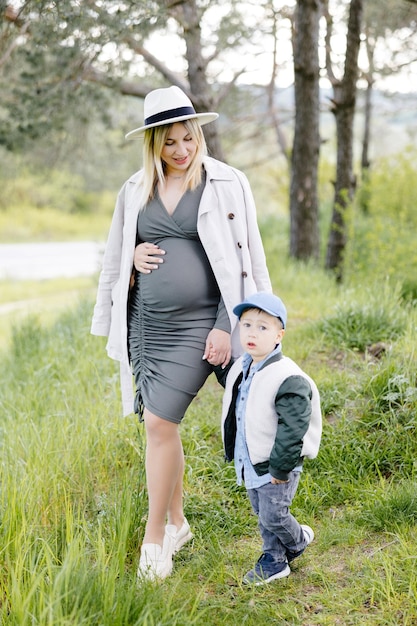 Mãe grávida e seu filho caminhando na floresta e passando tempo juntos