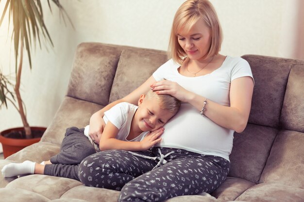 Mãe grávida e seu filho estão passando um tempo juntos em casa no sofá