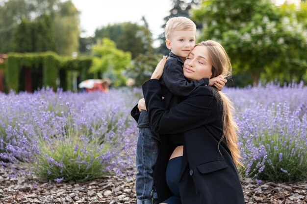 Mãe grávida e seu filho passando um tempo juntos no parque abraçando e sorrindo