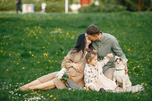 Mãe grávida e sua filha e marido sentado em uma grama em um parque