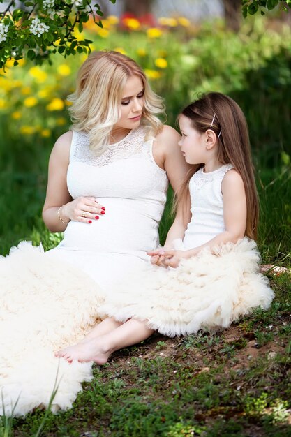 Mãe grávida e sua filha pequena se divertem ao ar livre. Família parece retrato