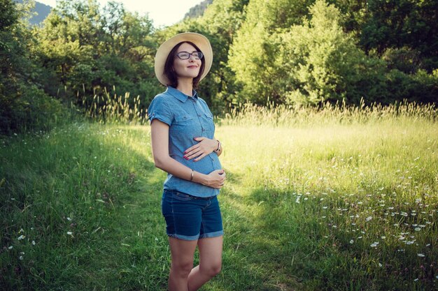 Mãe grávida esperando no campo de verão O conceito e a ideia de saúde, felicidade e maternidade