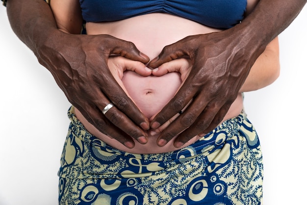 Mãe grávida O pai do homem afro-americano negro étnico da mãe grávida faz um coração na barriga de grávida.