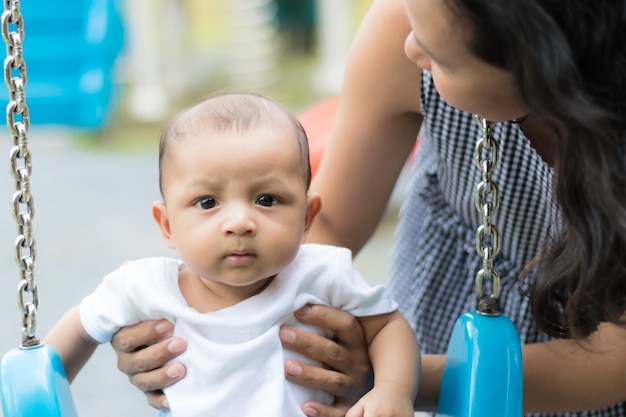 Foto mãe jogando swing com bebê no parque infantil