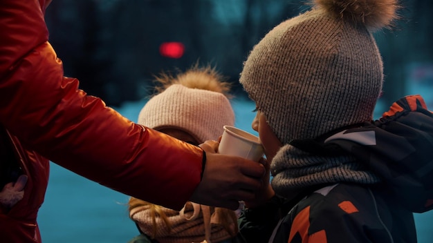 Mãe jovem dá bebidas quentes a seus filhos