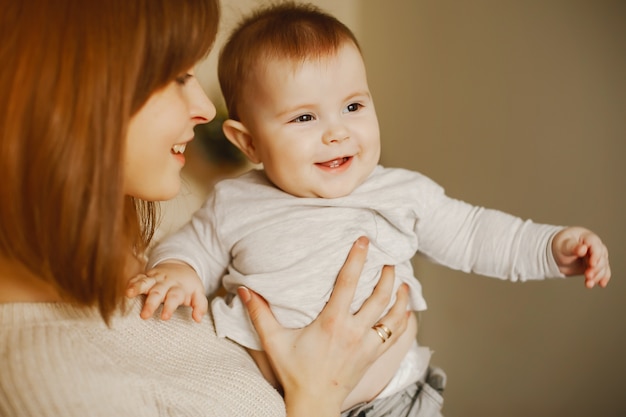 Mãe jovem e bonita, brincando com seu filho em casa