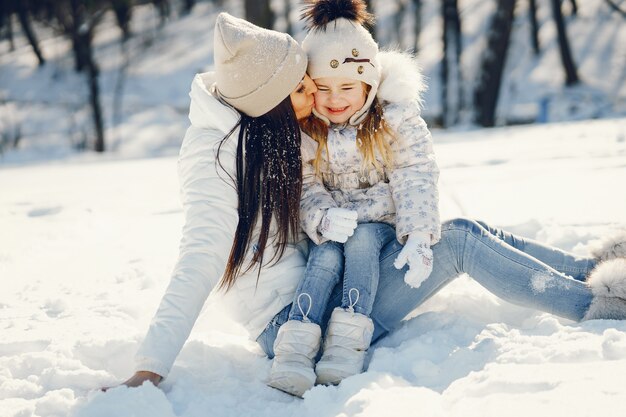mãe jovem e elegante, brincando com sua filha pouco fofa no parque de neve de inverno
