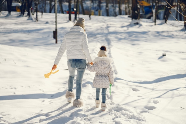 mãe jovem e elegante, brincando com sua filha pouco fofa no parque de neve de inverno